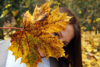 Close-up of young woman on yellow maple leaves during autumn