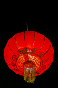 Illuminated lantern hanging against black background