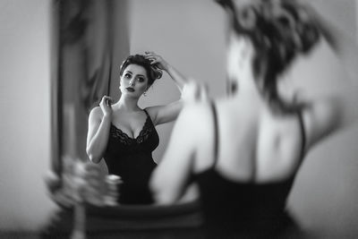 Young woman looking away while sitting on mirror