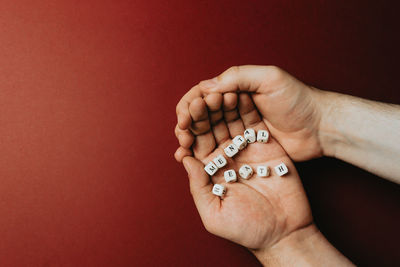 Close-up of hand holding hands against orange background