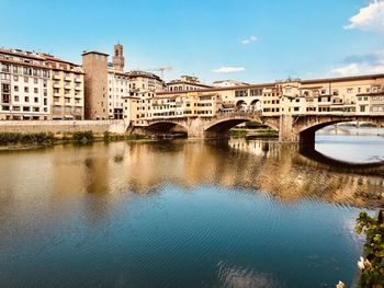 Arch bridge over river in city against sky