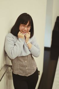 Portrait of young woman standing against wall