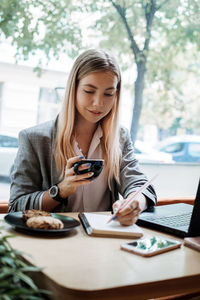 Young woman using mobile phone on table