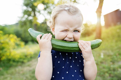 Portrait of little girl biting in cucumber