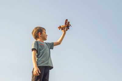 Rear view of woman with arms raised standing against clear sky