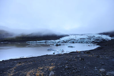 Scenic view of lake by snowcapped mountain against sky