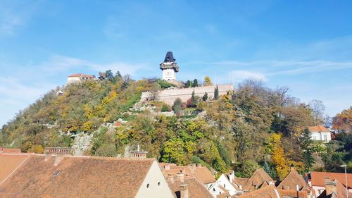 Low angle view of buildings on hill against blue sky