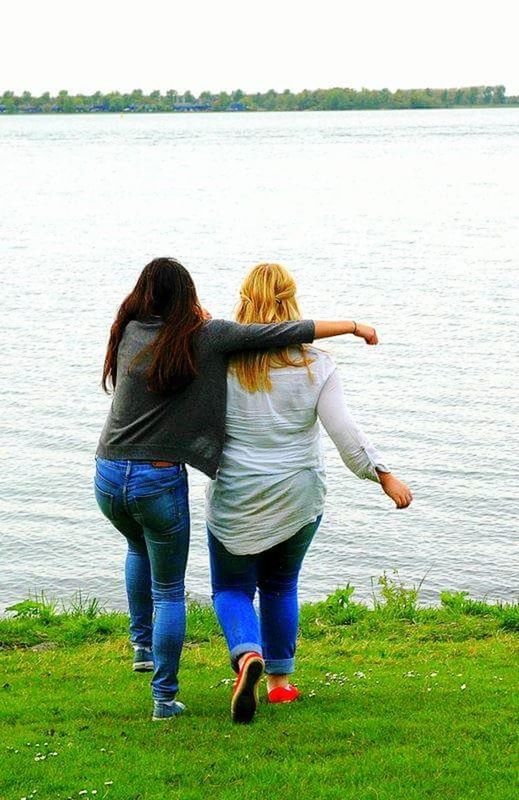 water, rear view, full length, two people, togetherness, casual clothing, leisure activity, women, day, nature, grass, bonding, adult, lake, friendship, standing, positive emotion, people, outdoors, jeans, hairstyle