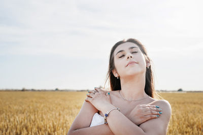 Young woman sitting on field against sky