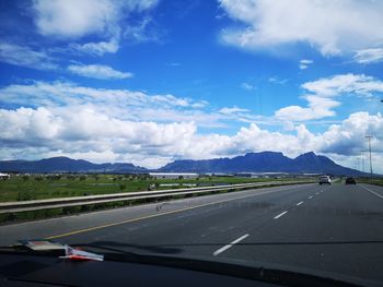 Road against cloudy sky seen through car windshield