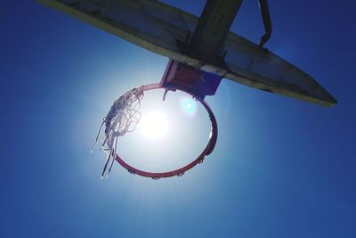 Low angle view of bright sun against clear blue sky