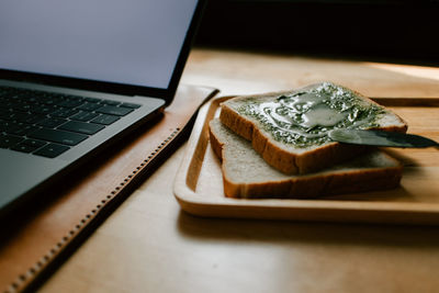 High angle view of laptop and green tea jam bread on table.