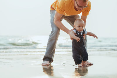 Full length of father and son at sea shore