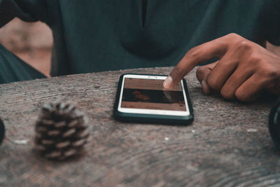 Close-up of hand holding smart phone on table