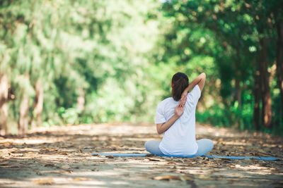 Rear view of young woman practicing yoga in at park