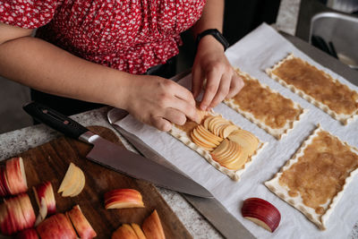 Midsection of young adult women making pastry with apples