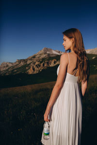 Young woman on field against clear blue sky