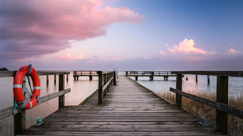 Pier over sea against sky during sunset