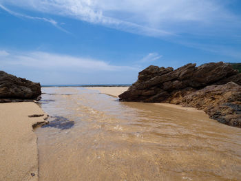 Scenic view of rocks on beach against sky