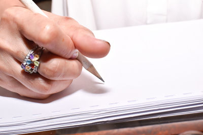 Cropped hand of woman writing on book