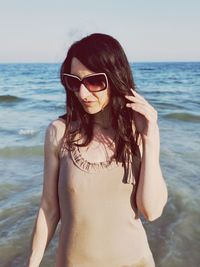 Young woman wearing sunglasses while standing on beach