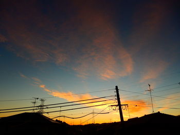 Low angle view of silhouette electricity pylon against sky during sunset