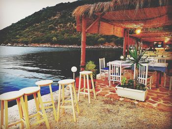 Chairs and tables in swimming pool against trees