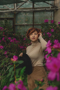 A beautiful plus size young woman standing among the green plants of the greenhouse. 