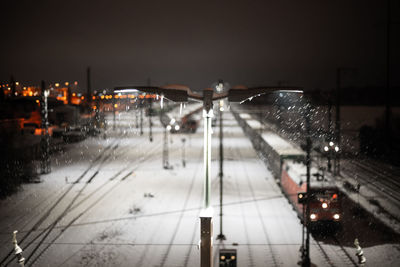 Illuminated railroad tracks in city at night during winter