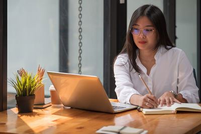 Woman looking away while sitting on table