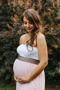 Smiling pregnant woman standing on field