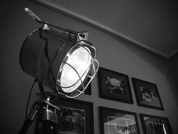 Low angle view of illuminated electric lamp against wall