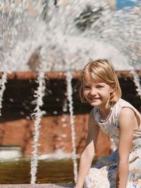 Portrait of young woman standing against waterfall