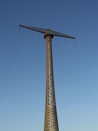 Low angle view of rollercoaster against clear blue sky