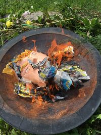 High angle view of paper burning in fire pit on field