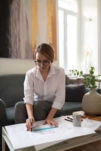 Young architect working on blueprint in cozy studio