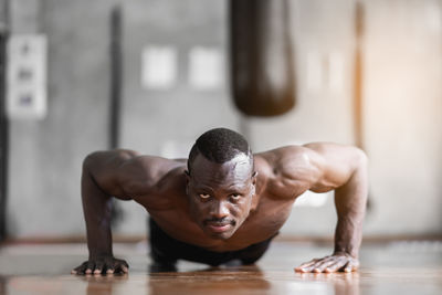 Low angle view of shirtless man sitting on floor