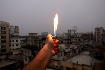 Midsection of man holding glass against buildings in city against sky