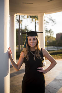 Female college student posing in courtyard with graduation cap