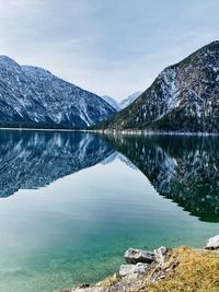 Scenic view of lake by mountains against sky