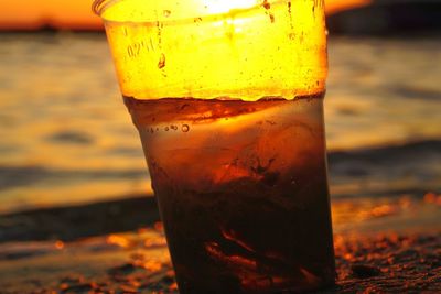 Close-up of yellow water on beach against sky during sunset