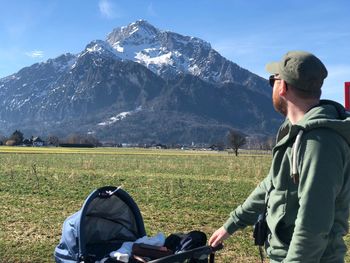 Man with baby stroller standing against mountain