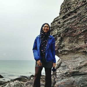 Portrait of smiling woman standing by sea 