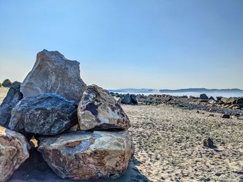 Rocks on beach against clear sky