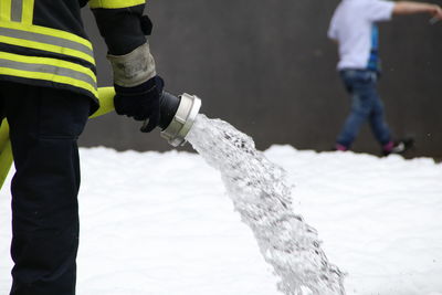 Midsection of man holding fire hose while standing on land