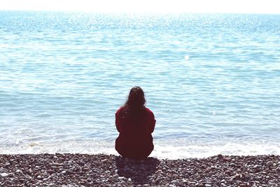 Rear view of woman sitting on beach