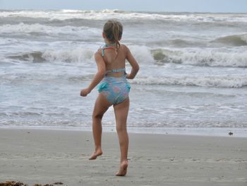 Rear view of girl running at beach