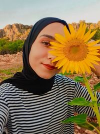 Portrait of beautiful young woman with yellow flower