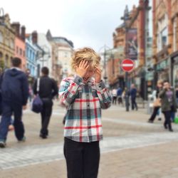 Annoyed boy standing on street in city