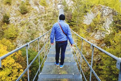 Rear view of man walking on footbridge